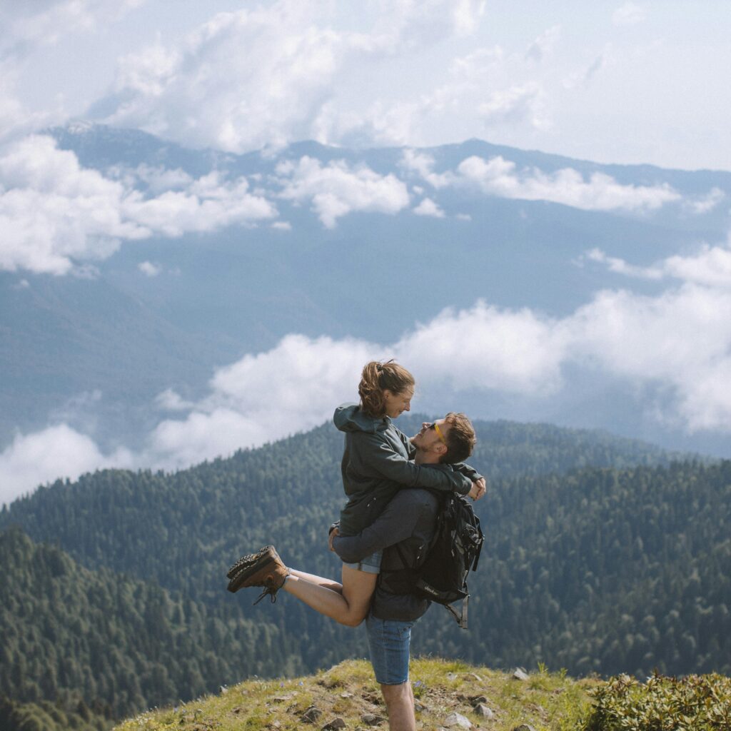 pexels-photo-4763909-4763909 Adventure-loving couple embracing on a mountain peak with breathtaking views of clouds and forests.