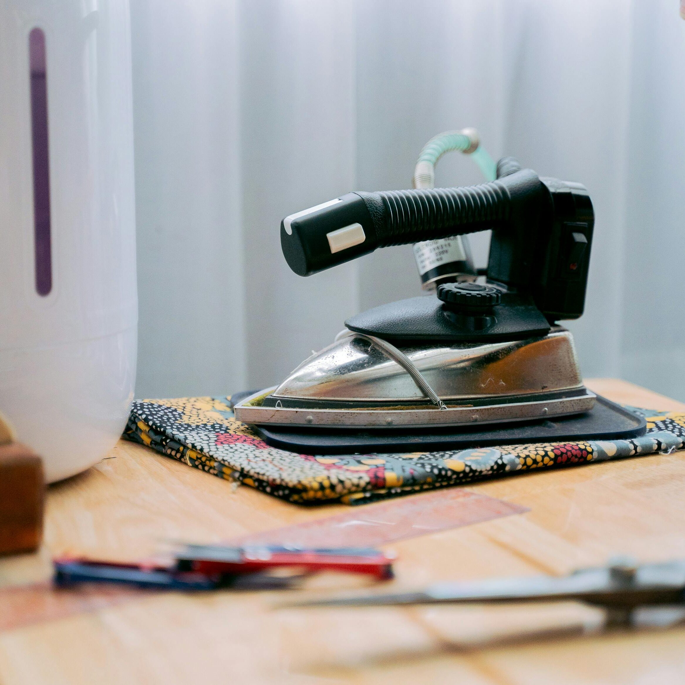 pexels-photo-6358818-6358818 Retro iron on a wooden table beside other household items, evoking nostalgia.